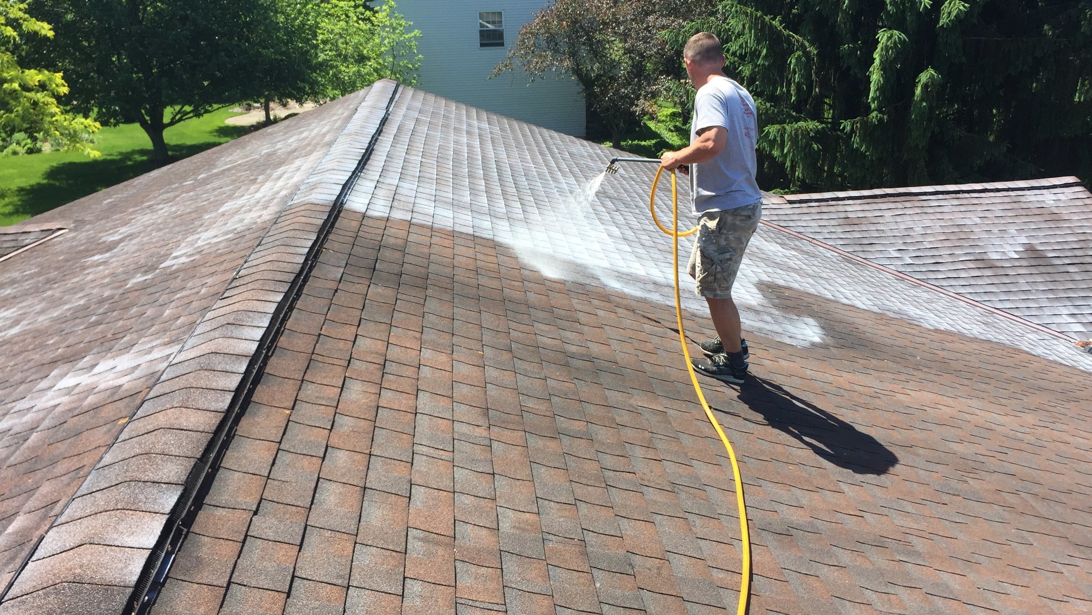 Roof restoration technician spraying a residential roof